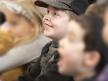Young boy in black cap sat in family theatre audience.