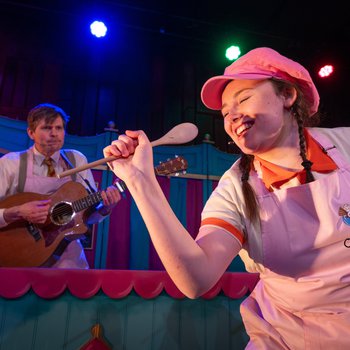 Women in pink hat singing into a wooden spoon