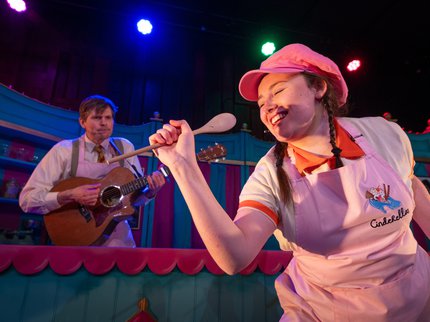 Women in pink hat singing into a wooden spoon