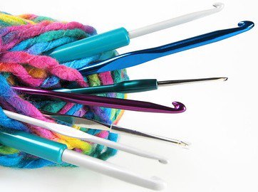 Several coloured crochet hooks held together with strands of yarn