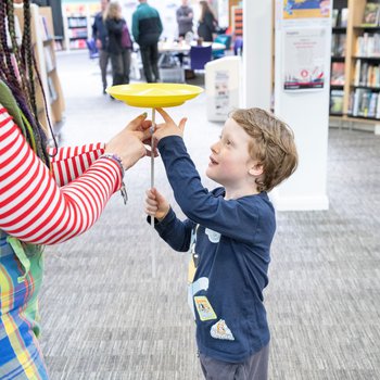 boy spinning a plastic plate with the help of a circus skills performer