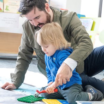 man and young child doing a floor-based art activity