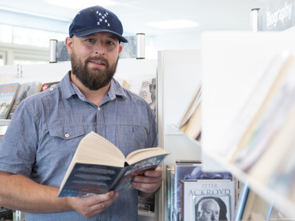 A man wearing a blue cap holds a book