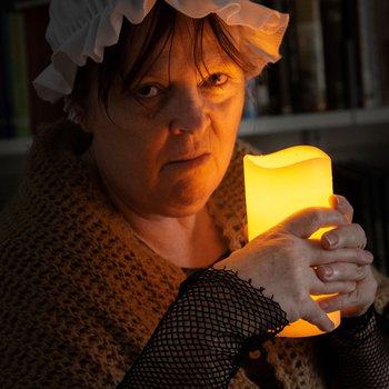 A person in costume grimaces by candlelight