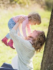 A parent lifting a child into the air and smiling