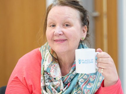 Person smiling and holding a mug with Places of Welcome written on it