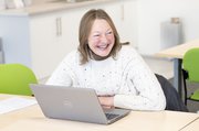 Adult learner smiling sat at a laptop.