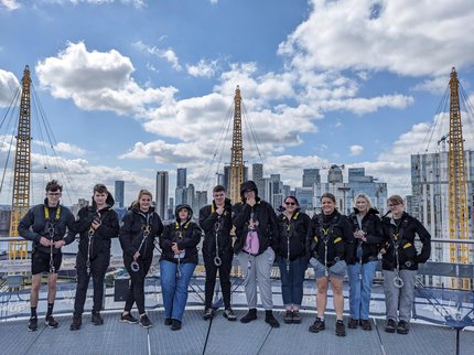 Inspire College students stood on the top of the O2 in London, wearing harnesses after climbing it.